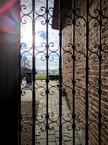 a view from a door through a wrought iron gate at Maison Lion Luxe gastenverblijf in Borgloon