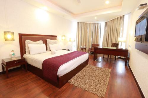 a hotel room with a bed and a desk and a television at The Bentley Seaside Boutique Hotel in Chennai