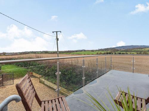 a balcony with a bench and a view of a field at The Barn At Whitefields in Walcot