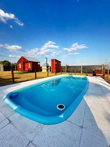a blue swimming pool with a red house in the background at La Vita CdelU in Concepción del Uruguay