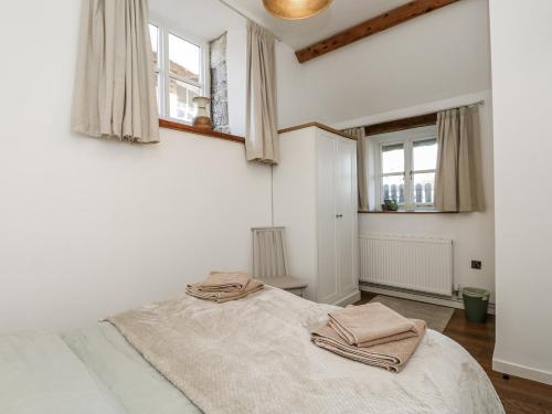 a white bedroom with a bed and two windows at Sheepwash Barn in Freshwater