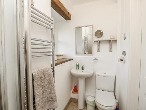 a white bathroom with a toilet and a sink at Sheepwash Barn in Freshwater