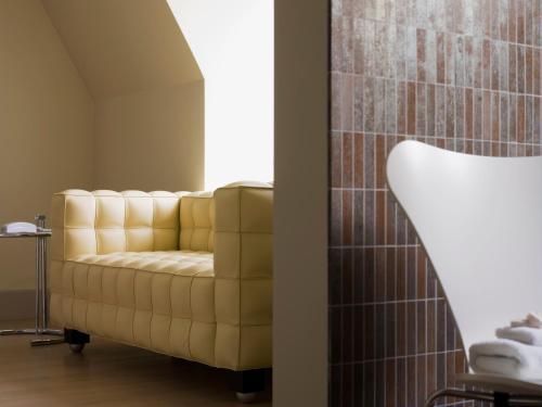 a living room with a yellow couch and a window at Hotel Recour in Poperinge