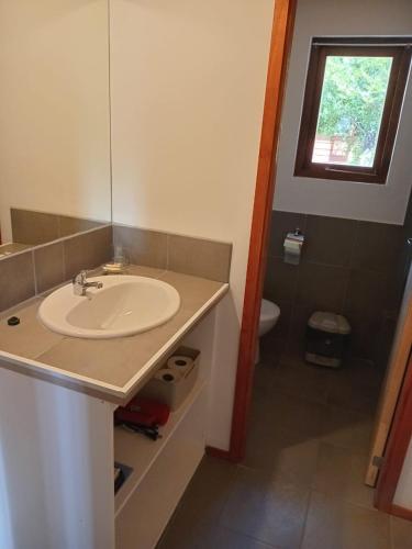 a bathroom with a sink and a toilet and a window at Cabañas del Oeste in San Carlos de Bariloche