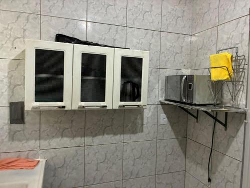 a bathroom with two windows and a microwave on a wall at Proximo ao Shopping e Aeroporto 2 Quartos com Ar e TV a Cabo in Várzea Grande