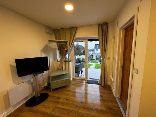 a living room with a television and a sliding glass door at Garden Studio in Bristol