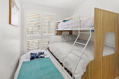 a small bedroom with a bunk bed with a ladder at Serenity - Pet Friendly with Spa & Waterfront in Sanctuary Point