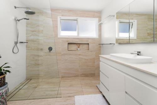 a white bathroom with a shower and a sink at Serenity - Pet Friendly with Spa & Waterfront in Sanctuary Point