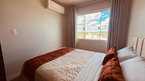 a bedroom with a bed in front of a window at Apartamento com ar condicionado e lava e seca in Cascavel