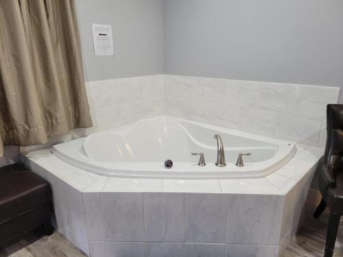 a white bath tub in a bathroom with a chair at Cobourg Inn in Cobourg