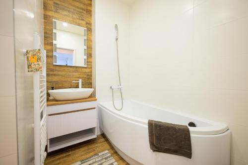 a bathroom with a white tub and a sink at Birdhouse Apartments in Prešov