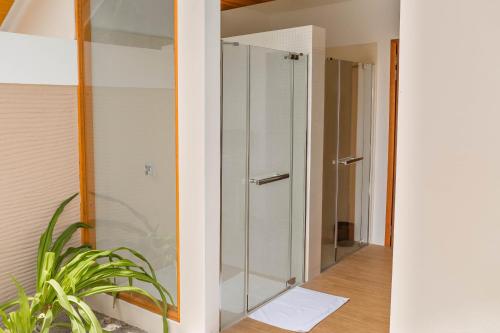 a glass shower in a bathroom with a plant at Kudafushi Resort & Spa in Raa Atoll