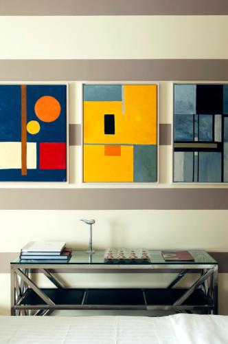 a room with a table with four paintings on the wall at Hotel Recour in Poperinge