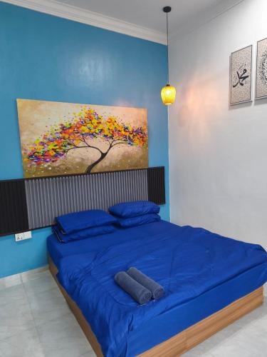 a bedroom with a blue bed with a painting on the wall at Anna Homestay Penarik Private Pool in Kampong Ru Sepuloh