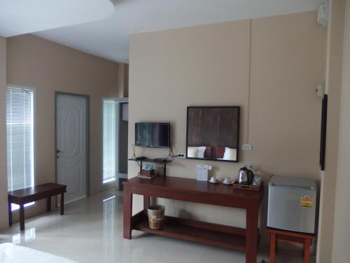 Muaan Resort في محافظة سوفانبوري: غرفة معيشة مع طاولة وتلفزيون