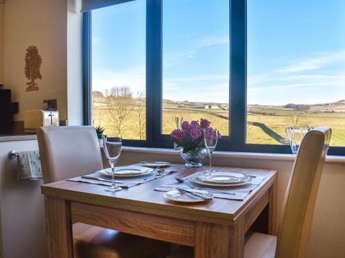 a table with glasses and a vase of flowers at The Wolfs Den - Uk49083 in Winewall