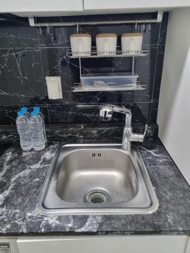 a kitchen counter with a sink and water bottles at ValueStay Hotel 9A in Seoul