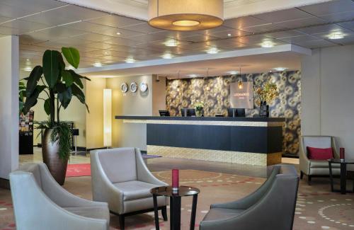 a lobby with a waiting area with chairs and a counter at Leonardo Hotel Hamburg City Nord in Hamburg