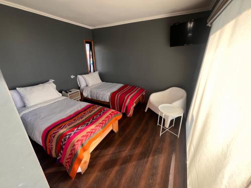 a bedroom with two beds and a table and a chair at Chagual Los Vilos Lodging in Los Vilos
