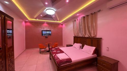 una camera da letto con un letto con luci rosa sul soffitto di Camara Homes6 a Saint-Louis