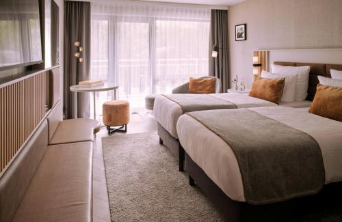 a hotel room with two beds and a window at Leonardo Royal Hotel Baden- Baden in Baden-Baden