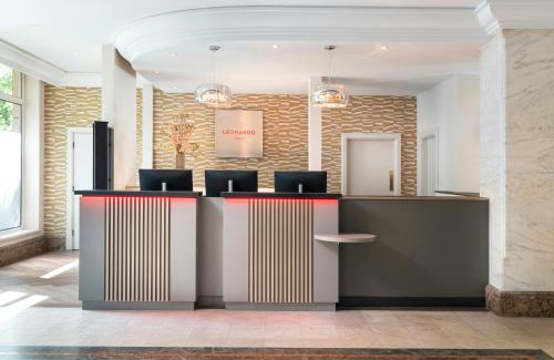 a lobby with a reception desk with chairs at Leonardo Hotel Düsseldorf City Center in Düsseldorf