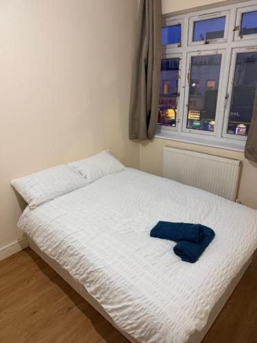 a white bed with a blue towel on it at Prentis Road in London