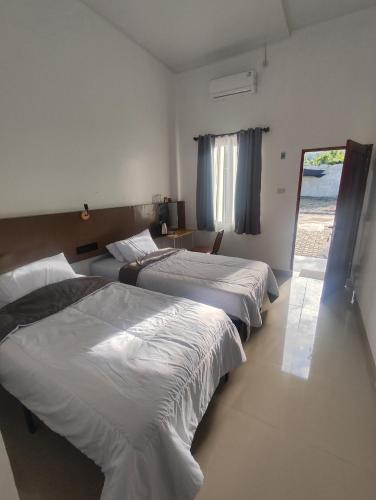 a room with three beds and a window at Hotel Sarijadi Pangururan in Pangururan