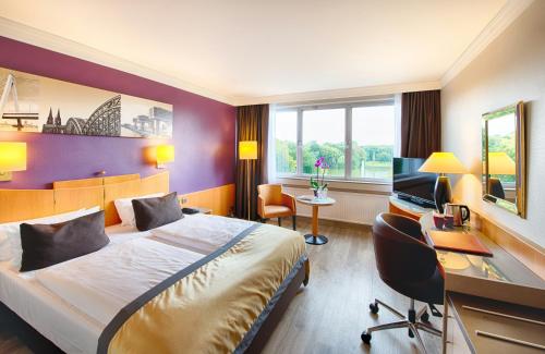 a hotel room with a bed and a desk at Leonardo Royal Hotel Köln - Am Stadtwald in Cologne
