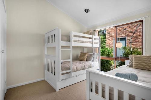 a bedroom with a white bunk bed and a window at Blenheim Beach Retreat in Vincentia