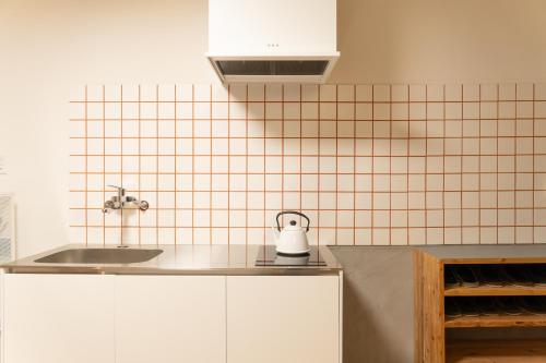 a kitchen with a sink and a tiled wall at one space 泊まれるコワーキングスペース in Kawatana