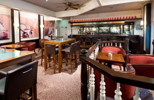 a restaurant with tables and chairs and a bar at Leonardo Hotel Köln Bonn Airport in Cologne