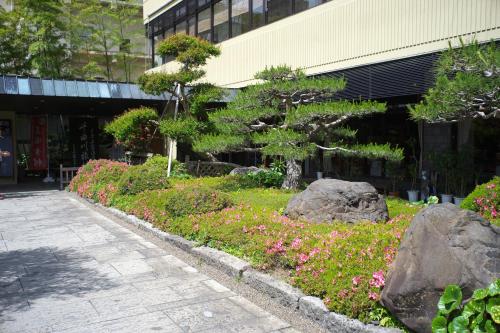 a garden with rocks and flowers in front of a building at Kamiyamada Hotel in Chikuma
