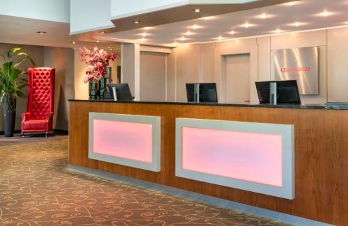 a lobby with a reception desk with pink lights at Leonardo Hotel Mönchengladbach in Mönchengladbach