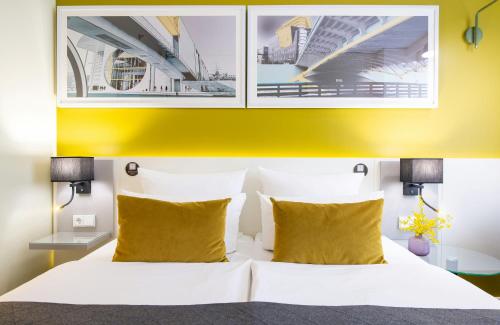a bedroom with a white bed with yellow pillows at Leonardo Hotel Berlin Mitte in Berlin