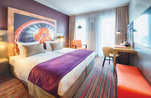 a hotel room with a large bed and a desk at Leonardo Hotel Munich City South in Munich