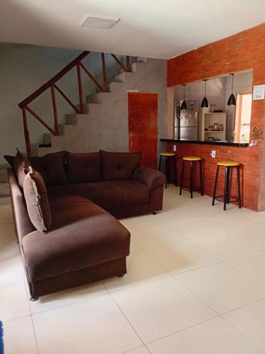 a living room with a brown couch and a staircase at Casa completa in Marechal Deodoro