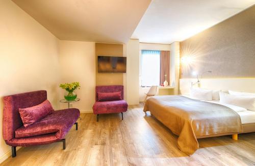 a hotel room with a bed and a chair at Leonardo Hotel Berlin Mitte in Berlin