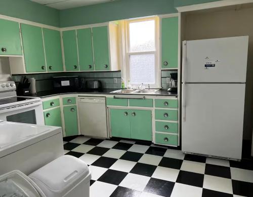 a kitchen with green cabinets and a black and white checkered floor at Falls Retreat - Walk to the Falls, the Casino and all Downtown Restaurants - Across from the Aquarium in Niagara Falls