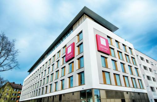 a building with red signs on the side of it at Leonardo Royal Hotel Ulm in Ulm