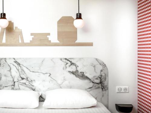 a bedroom with a bed with a marble headboard at Hôtel ibis Styles Vichy Centre in Vichy
