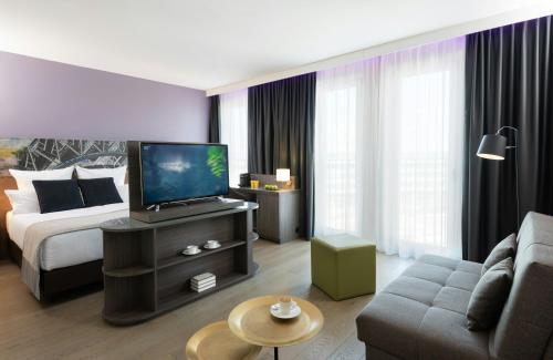 a hotel room with a bed and a television at Leonardo Hotel Munich City East in Munich