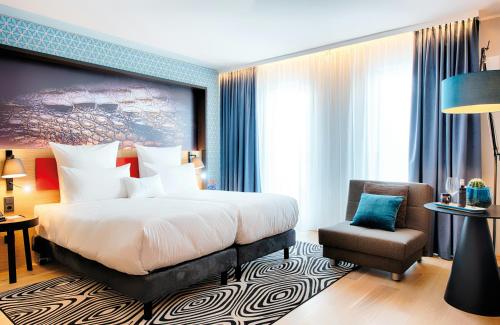 a hotel room with a bed and a chair at NYX Hotel Munich by Leonardo Hotels in Munich