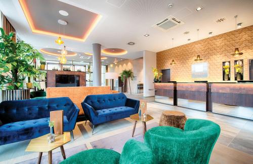 a lobby with blue couches and a bar at Leonardo Royal Hotel Ulm in Ulm