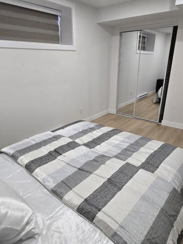 a bedroom with a bed with a striped blanket at Cozy 1-Bedroom Private Basement Suite in Winnipeg with separate entrance in Winnipeg