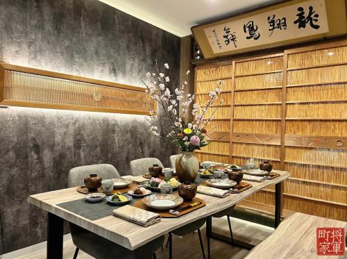 a dining room table with a vase of flowers on it at 将軍町家 in Nagoya