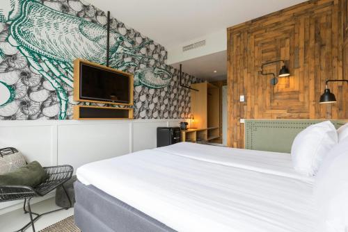 a bedroom with a bed and a tv on a wall at Leonardo Hotel Vinkeveen Amsterdam in Vinkeveen