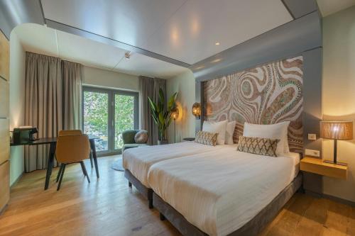 a bedroom with a large bed and a desk at Leonardo Hotel Breda City Center in Breda