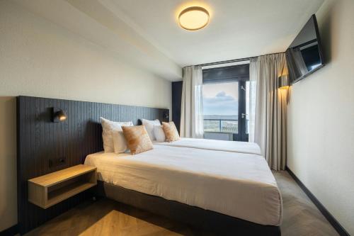 a hotel room with a large bed with a window at Leonardo Hotel IJmuiden Seaport Beach in IJmuiden