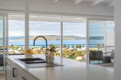 a white kitchen with a view of the ocean at The View, Albany Holiday House in Albany